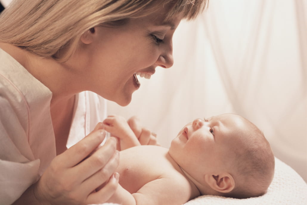 A mother holds and smiles at her new born baby